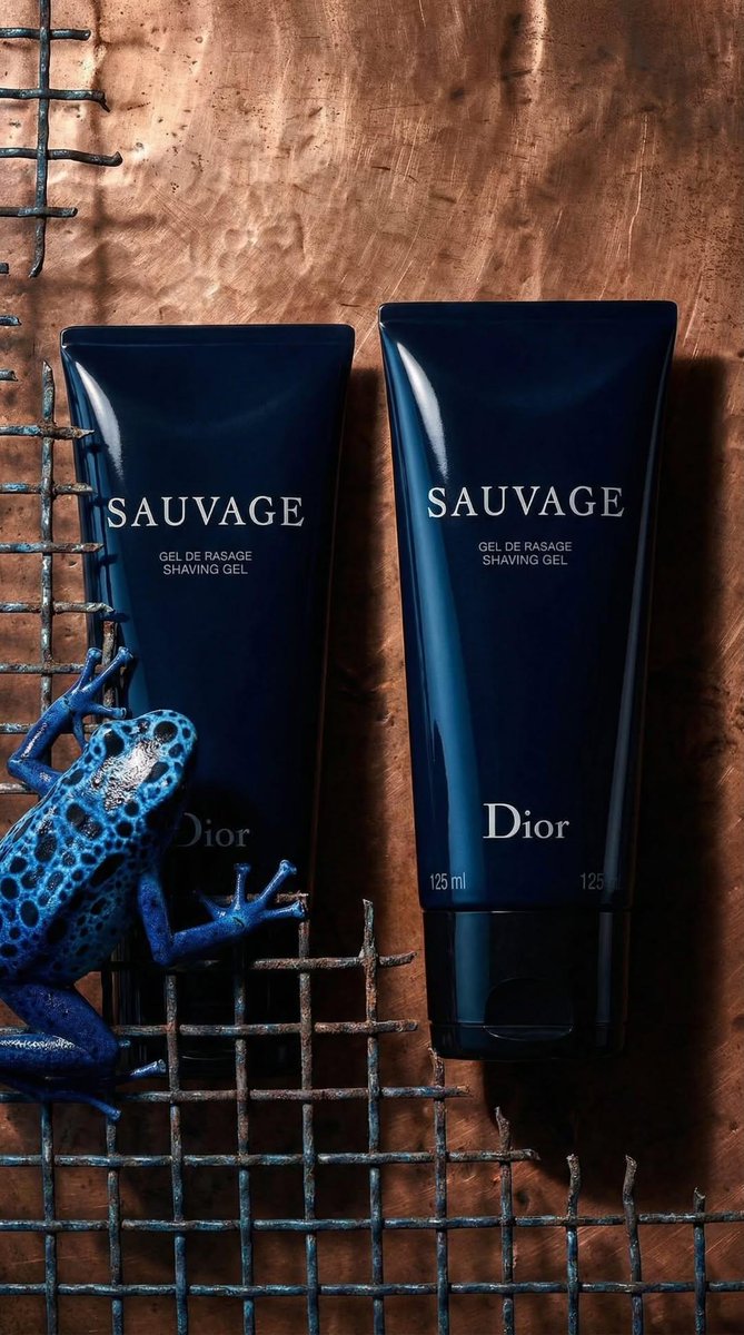 奢华产品摄影：一支哑光黑色剃须凝胶管，标签上印有“SAUVAGE”和“Dior”，斜放在两块古铜色铜板上，铜板上雕刻着复古解剖学青蛙插图（一只青蛙骨骼图，一只青蛙轮廓图）。背景为…