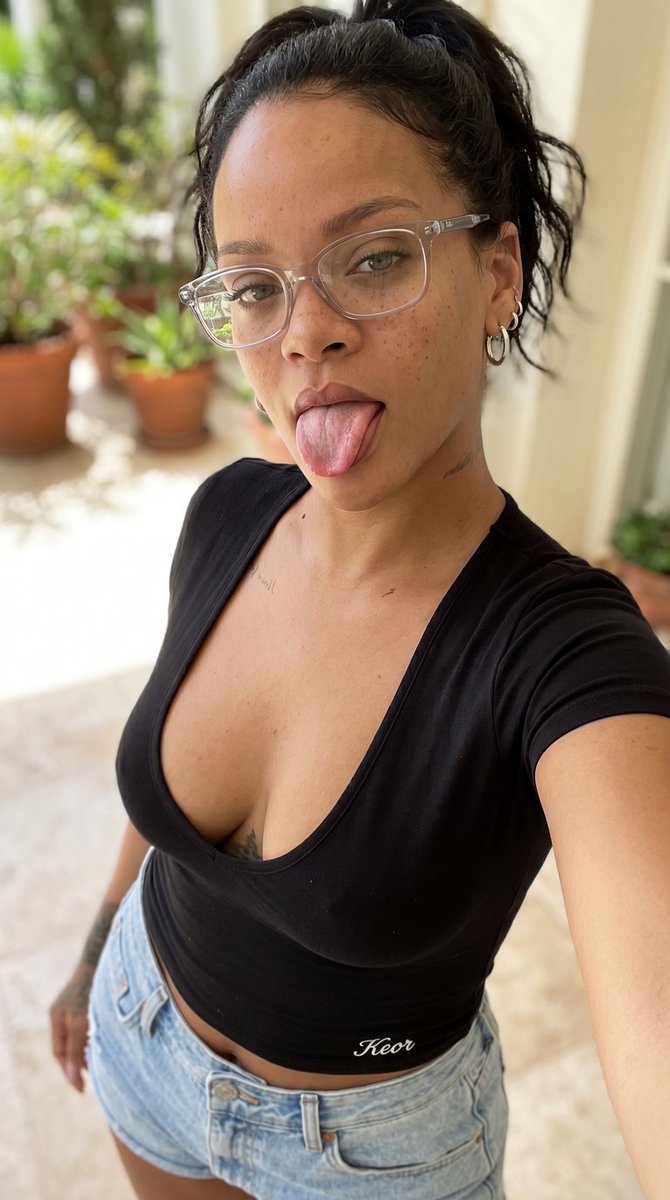 垂直特写自拍，迷人的凯莉·詹娜（Kylie Jenner），黑发俏皮地伸出舌头，穿着橙色低胸上衣和牛仔短裤，面部可见雀斑，戴着眼镜，橙色上衣下摆处绣有精致小巧的白色'Keor'字…