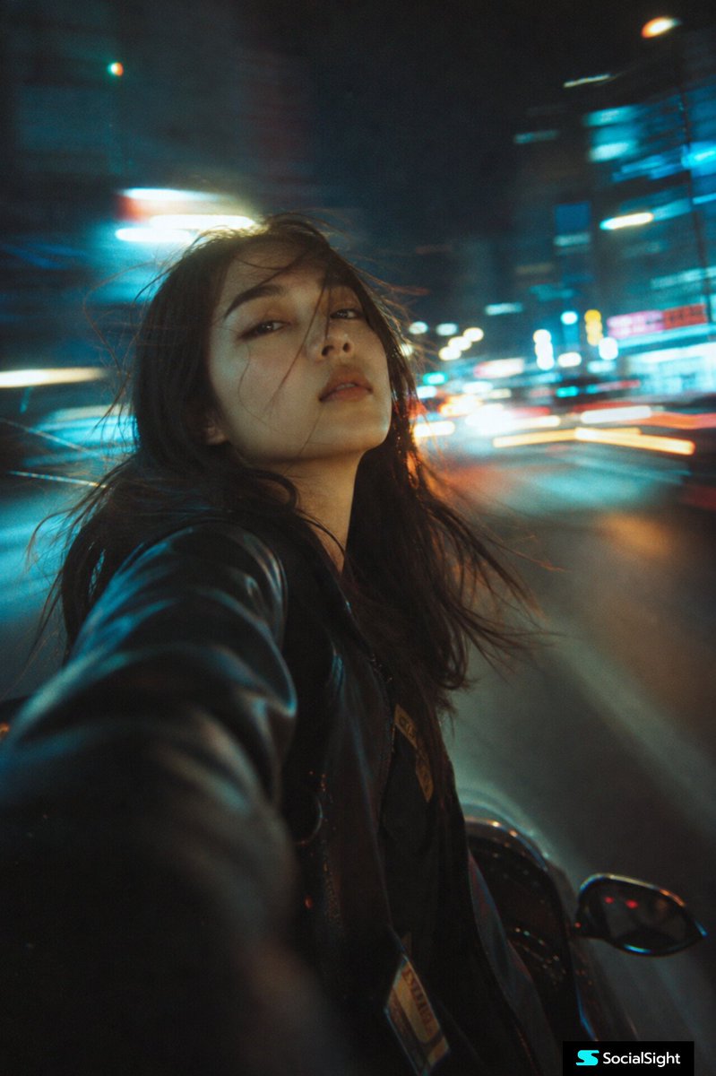 一位年轻女性骑行穿越城市的电影感夜景自拍，采用低位广角视角拍摄。柔和梦幻的运动模糊，路灯和车流的拉长光轨营造出赛博朋克光晕。霓虹蓝、青绿与暖琥珀色光线在背景中拖出条纹。浅景深，带…