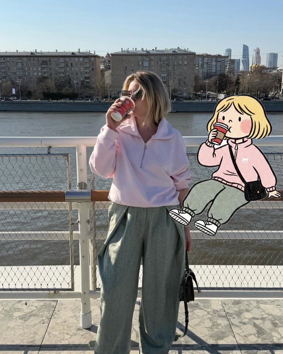 柔和的抓拍街头摄影,一位时尚女性站在河边渡轮甲板上,手持红色外带杯喝咖啡,晴朗午后光线,柔和粉彩色调,超大浅粉色半拉链卫衣,宽松灰色长裤,黑色单肩包,金色短波波头发型,戴着墨镜…