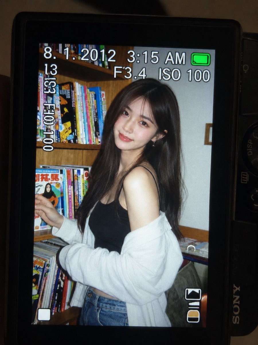 一张超精细的特写镜头：一台微型紧凑型数码相机的 LCD 屏幕在原本黑暗的室内房间中明亮发光。屏幕上是一张 2010 年代初期的随性傻瓜相机快照，画面中一位年轻东亚女性留着一头深色…