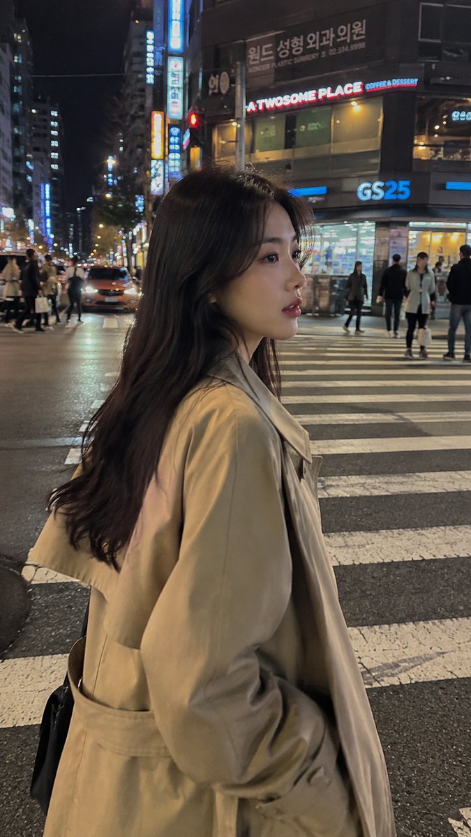超写实的随拍 iPhone 街头照片:一位美丽的年轻韩国女孩,夜晚穿过霓虹灯闪烁的首尔街道,从侧视角抓拍,电影感的都市氛围,自然的行走姿态,黑色长发随风飘动,身穿米色超大号风衣…