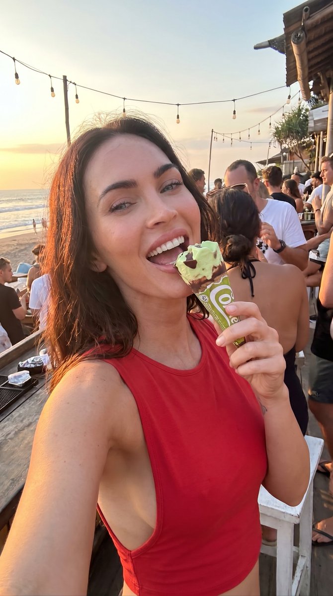业余特写微模糊自拍的美味惊艳意大利瘦削棕发女友 emily ratajkowski,正在舔食一个草莓奶油甜筒(cornetto gelato),并在日落时分一家繁忙的酒吧里大笑…
