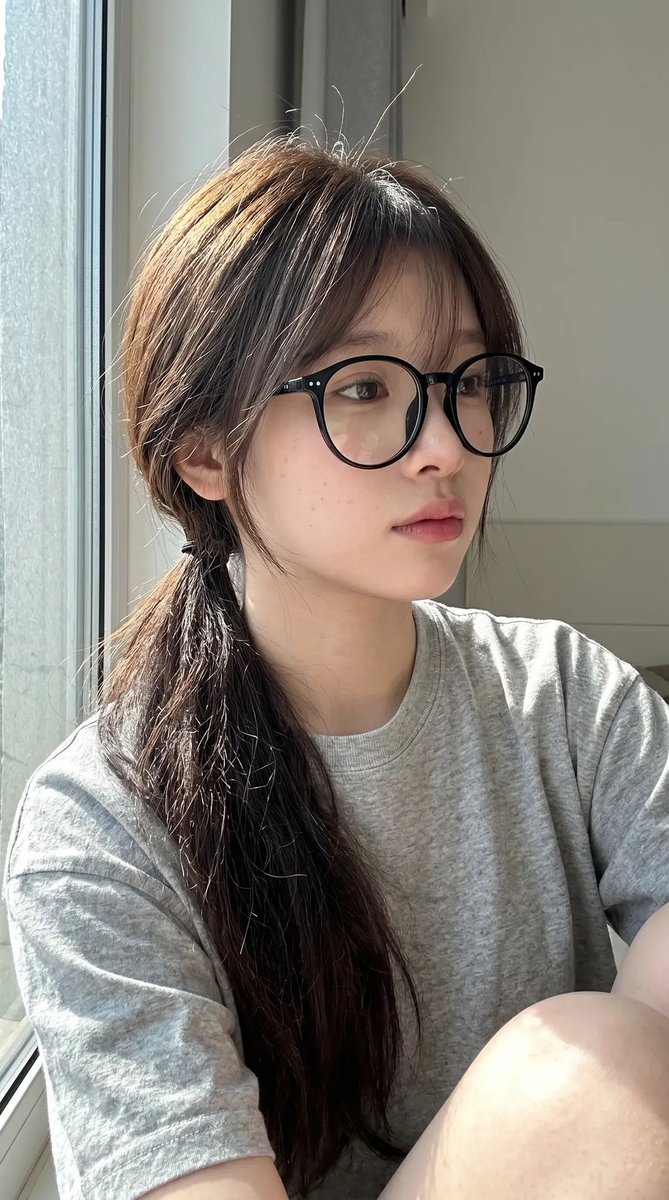 超写实抓拍式智能手机自拍照肖像：一位年轻东亚女性室内坐在一扇大窗户旁，处于明亮的自然日光下。保持与上传的面部参考高度相似的面部特征：柔和的椭圆形脸型、纤细的下颌线、自然偏窄的鼻梁…
