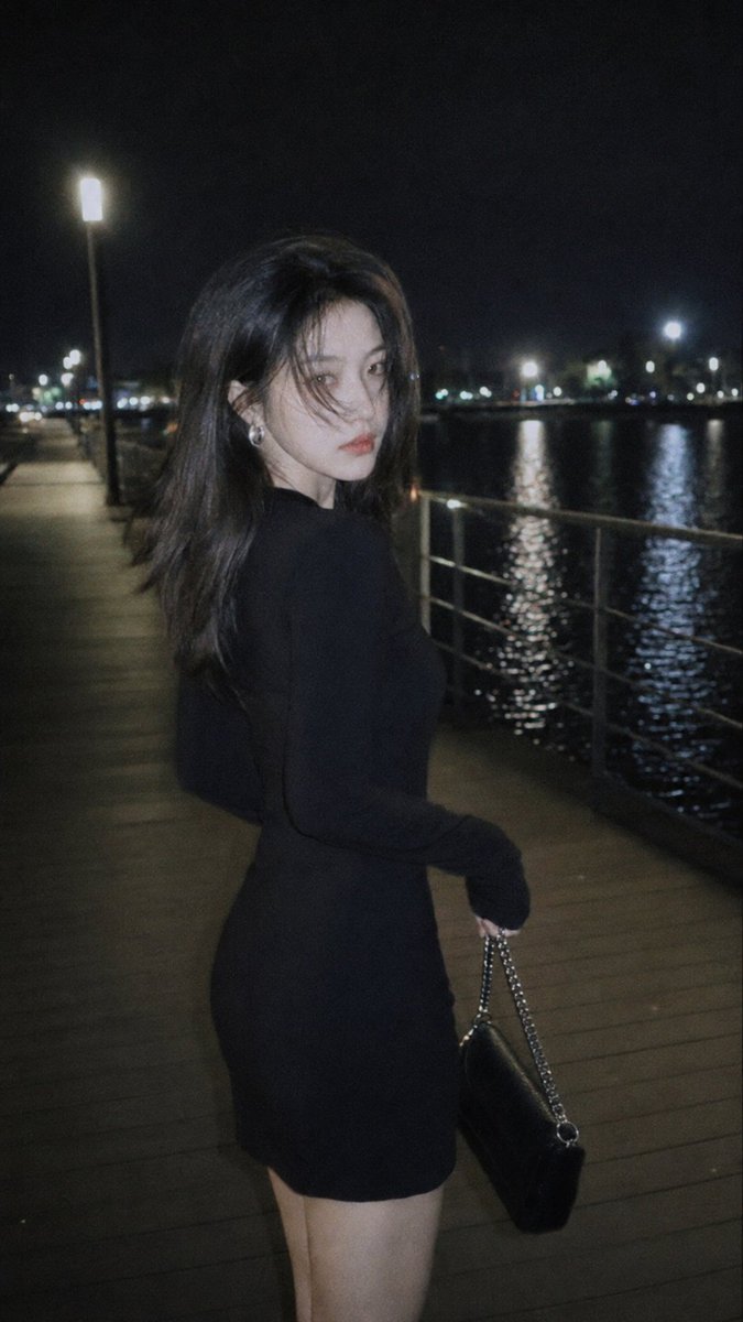 风格：CCD 柔光胶片摄影 概念：情绪感城市夜景街头人像 场景：夜晚的湖边栈道，街灯光芒，水面反光，栏杆步道 着装：修身黑色长袖连衣裙，银色耳饰，小型链条包 氛围：冷酷疏离，深夜…