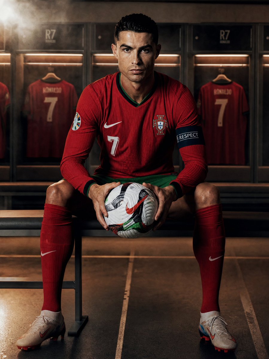 创作一张超写实的摄影作品：[team]球队的[footballer]坐在更衣室里，手持一个足球，全身正面视角，目光直视镜头。球员身穿官方球队球衣。戏剧性的侧光…