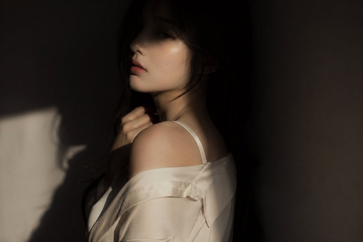 电影感编辑风格人像:韩国女团偶像,氛围微妙而迷人 服装:略宽松的真丝或柔软面料上衣,优雅且流动 姿势:躯干背向镜头,脸部仅部分可见,一只手抬起靠近领口或喉咙 表情:柔和而神秘,双…