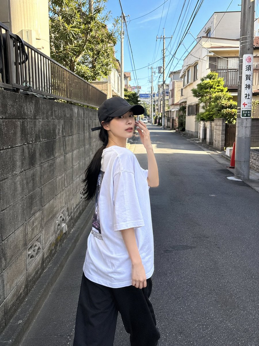 一位超美的年轻日本女性,拥有无瑕陶瓷般肌肤、自然红润的脸颊、光泽粉嫩的嘴唇、大而闪亮的杏仁眼,还有乌黑丝滑长发在风中肆意飞扬。她身着醒目的 oversized 亮红色校队夹克,内…