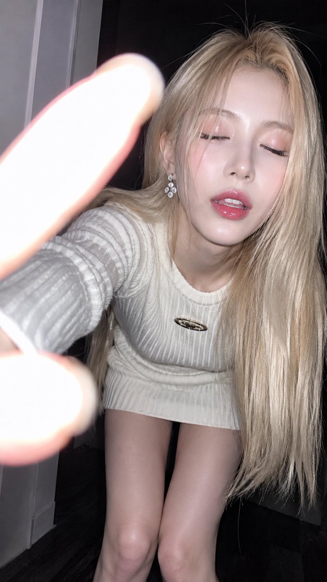 { "subject": { "description": "一名18岁以上的年轻成年女性,室内近距离闪光灯特写肖像。她向镜头前倾,营造出一种自然的自拍式瞬间。视觉形象由铂金色头…