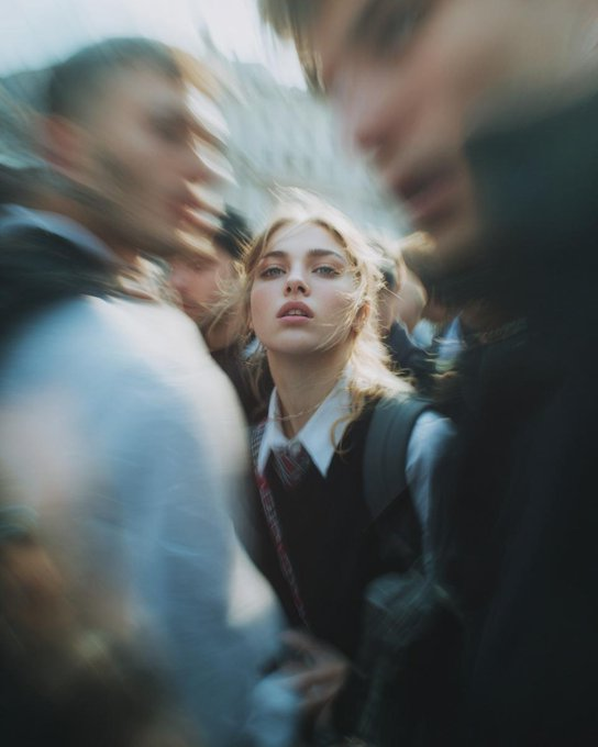 狗仔队风格的极近景特写照片，一位面部特征鲜明的女性，在毫无防备时猛然转向镜头。仅拍摄面部与肩膀，采用低角度仰拍。强烈的硬光直闪，高ISO颗粒感，原始抓拍的街头…