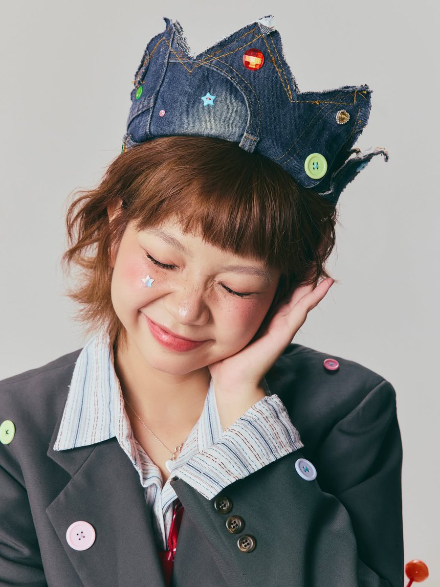 超写实编辑时尚肖像:一位俏皮的年轻女性,留着短款层叠栗棕色波波头与齐整的直刘海,柔和自然妆容配以玫瑰色腮红,鼻梁上有淡淡的雀斑,粉色光泽唇,长而卷翘的睫毛,搭配上挑眼线,一侧面颊…
