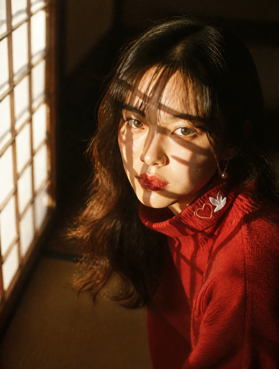 亲密的特写肖像:一位年轻的日本女性跪坐在纸糊障子门旁,傍晚金色的阳光透过障子的木格栅切割而入,在她的脸庞与发丝上投下锐利的几何网格阴影——比百叶窗更具戏剧性与棱角感。深情的、直视…