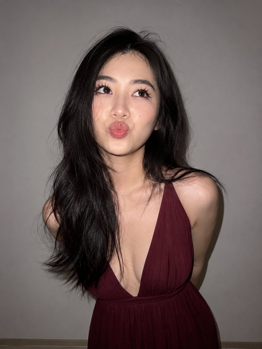 ChatGpt 图像 #chatgp 提示词 ~ 一张超写实的近距离闪光灯人像照,主体是一位年轻成年东亚女性,站在纯浅灰色墙壁前。她有一头浓密的乌黑长发,带有柔和的自然波浪和细微…