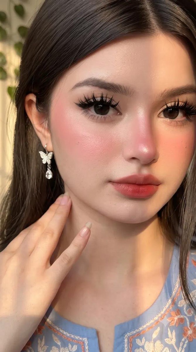 请原样保留她原有的面部特征。她天生容貌美丽，面部对称性完美。她应显得年轻且有女性魅力，拥有自然丰满的胸部，而非平坦的胸部。 这是一张室内特写自拍照，照片中是一…