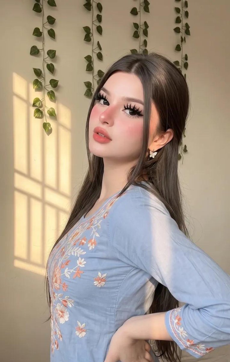 请原样保留她原有的面部特征。她天生容貌美丽，面部对称性完美。她应显得年轻且有女性魅力，拥有自然丰满的胸部，而非平坦的胸部。 这是一张室内特写自拍照，照片中是一位年轻女性，面容柔和…