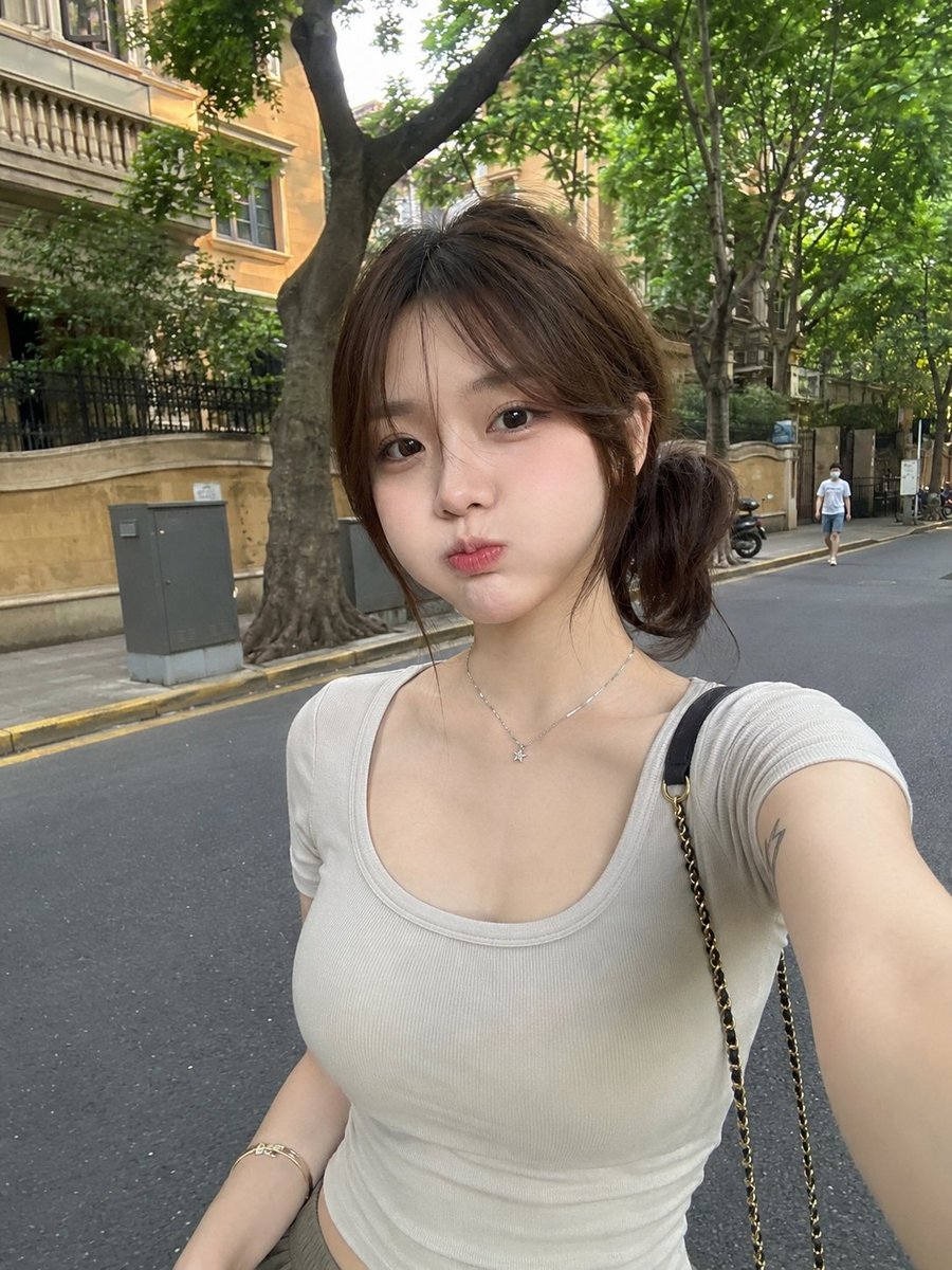 GPT image 2 via higgsfield Prompt 一张RAW、超写实的智能手机照片：一位美丽的年轻东亚女性，白天随意地站在一条安静的绿树成荫的城市街道上。她拥有…