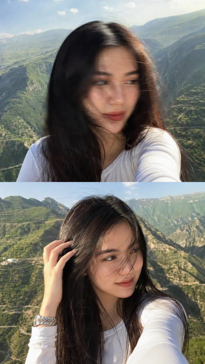 一张梦幻电影感的自拍照:一位美丽的年轻女子站在山顶观景点,长发笔直乌黑,拍摄于黄金时刻。她身穿一件修身白色长袖上衣,佩戴一只银色金属腕表。微风轻轻吹动她的头发拂过面庞,她柔和自然…