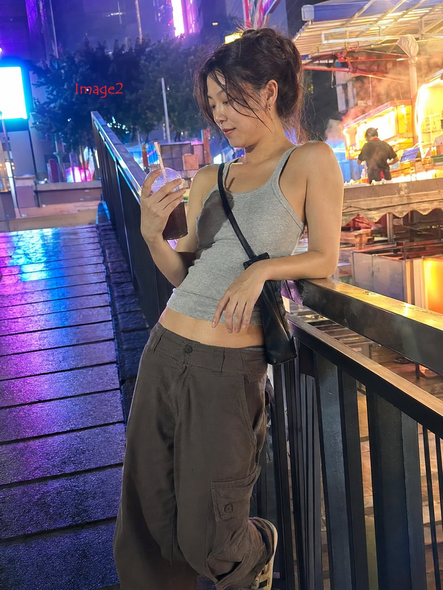 3:4，iPhone 17 35mm 镜头抓拍的真实生活照片。 主体：25 岁以上的中国女性，身材修长健美，自然的面部特征，穿着紧身灰色背心，因闷热潮湿而略微贴合皮肤，宽松工装裤…