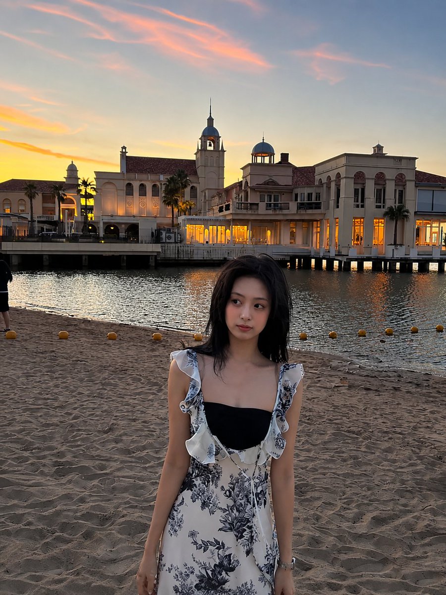 超现实电影感旅行照片：一位年轻的东亚女性站在沙滩上，沐浴在令人屏息的日落中，采用竖向 3:4 构图。她身穿一件精致的白色连衣裙，点缀着细腻的蓝色花卉印花，肩带为荷叶边设计，整体剪…