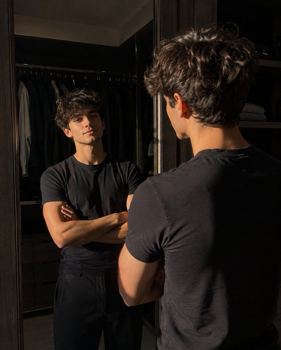 创作一张超写实的随性街头风格照片，作为参考图，画面中一位二十出头的年轻男子正在一家现代高档食品超市内漫步。拍摄角度为他的身后并略微偏侧，他正回头向左肩方向望去。他留着短而自然凌乱…