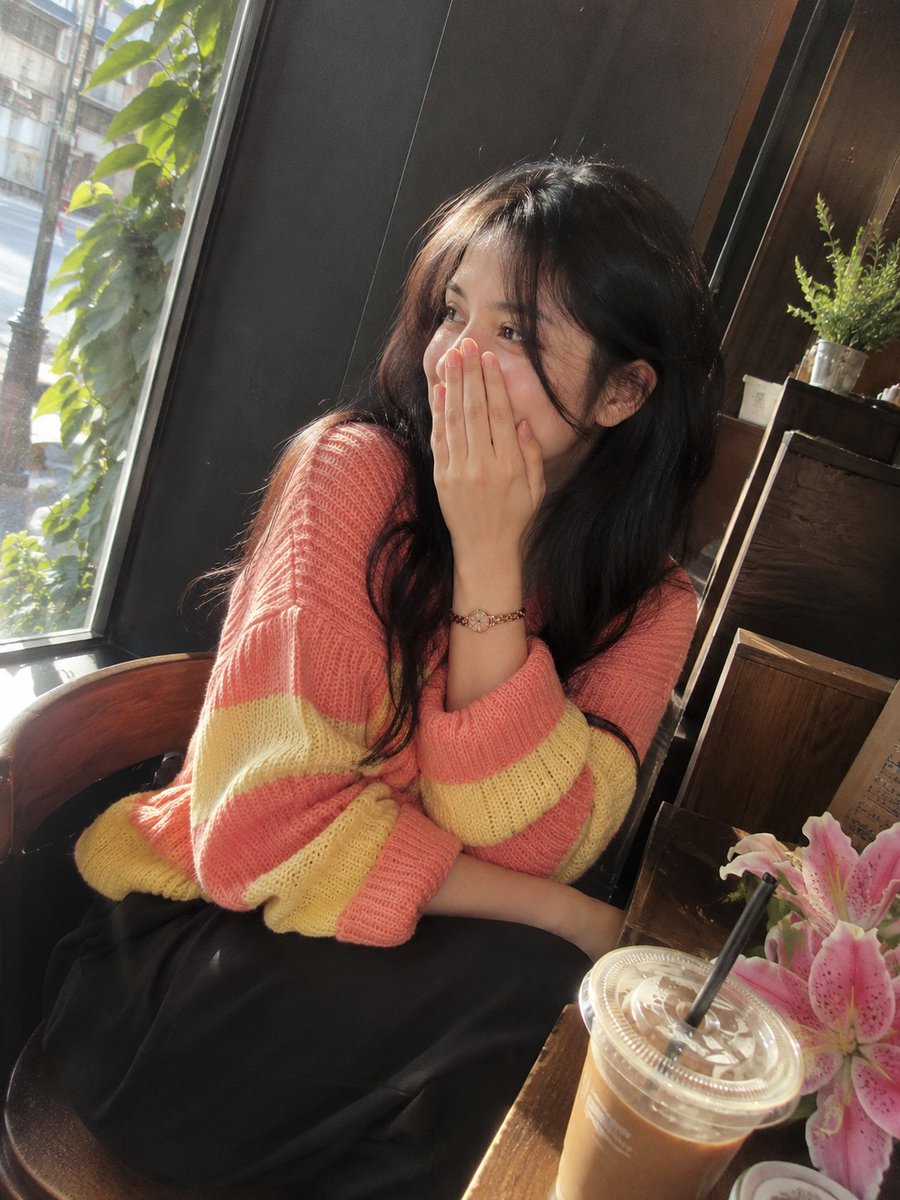 照片级写实风格的影院感咖啡馆肖像：一位美丽的成年女性，留着长而自然卷曲的深棕黑色头发，皮肤柔和泛光，五官精致，眼神富有表现力。她身穿宽松舒适的针织毛衣，交替呈…