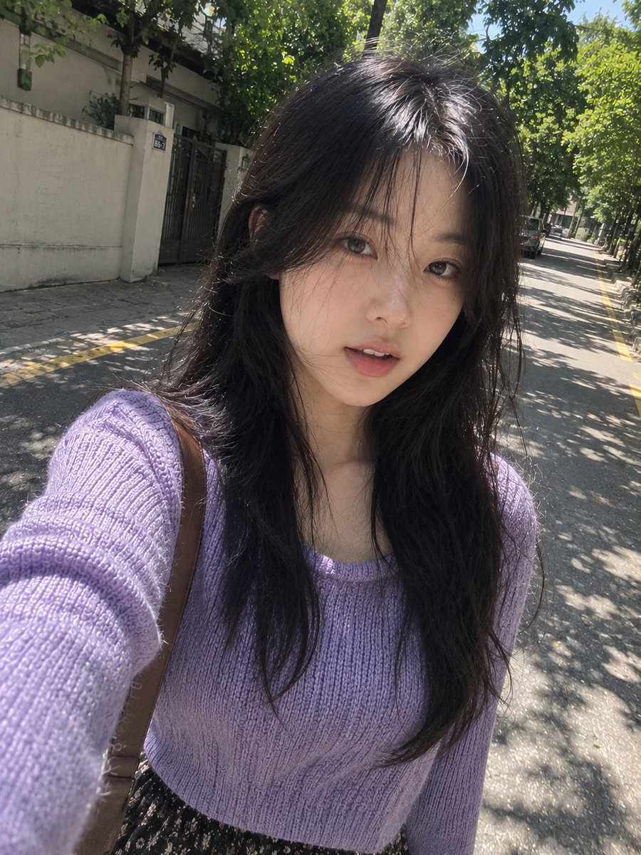 一张完全自然、照片写实风格的智能手机自拍照，画面中是一位年轻的东亚女性在一条安静的林荫街道上随意行走时拍摄，看起来就像是她自己一边走路一边用手机随手拍下的照片…
