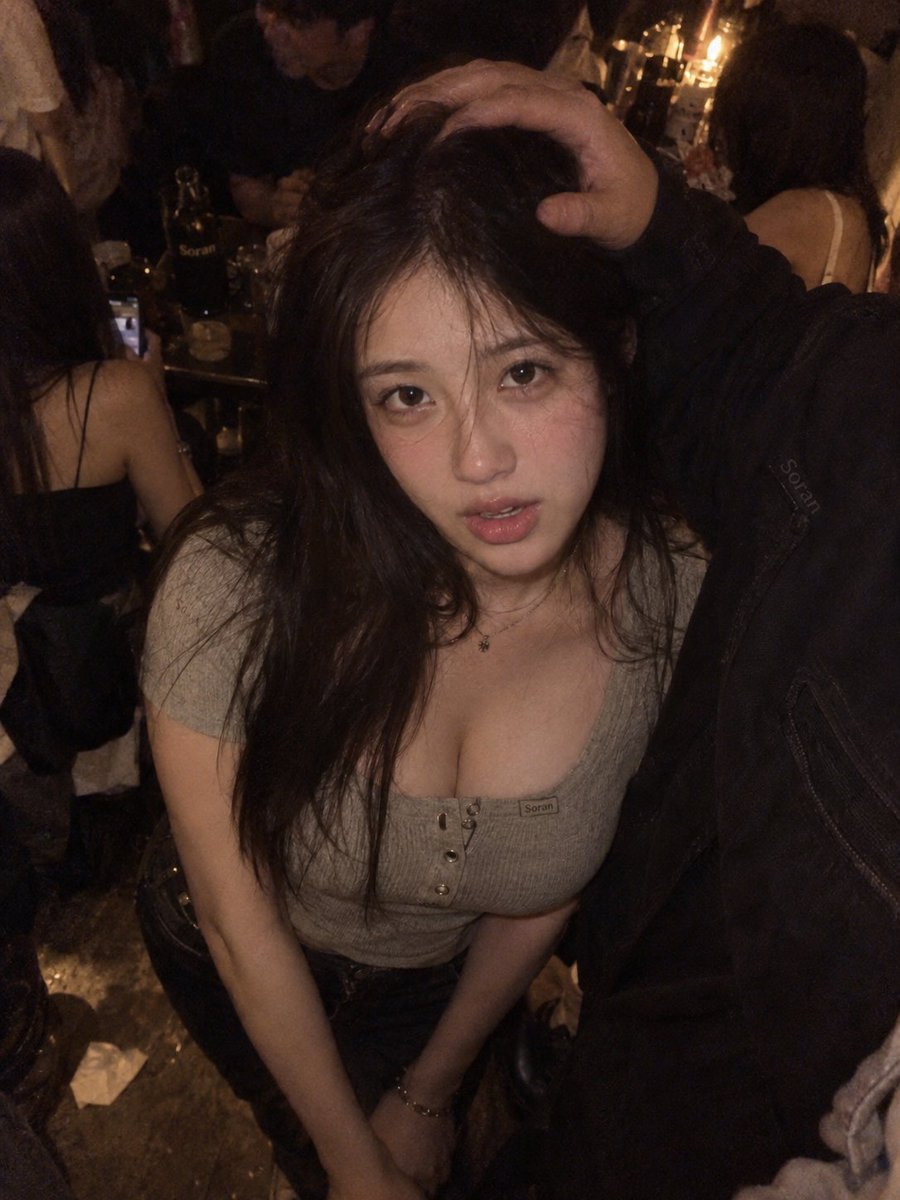 3:4 竖幅，真人写实夜间聚会快照风人像，成年东亚女性位于画面中央偏左，近距离高机位俯拍，摄影机明显高于人物眼睛。人物身体基本正向镜头，头部略微抬起，眼睛自然…