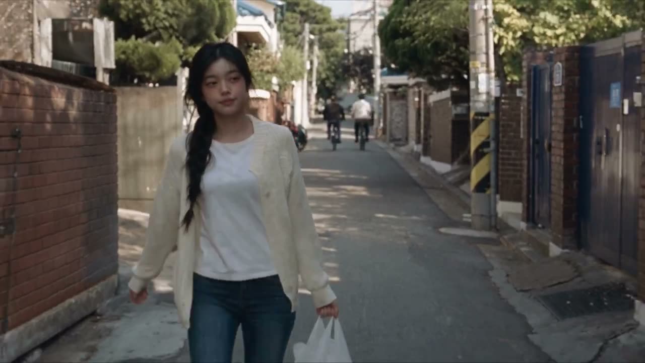 创建一个30秒、1080p超写实2000年代初DV家庭录像视频：一位年轻韩国女性在中午12点从社区超市穿过首尔老街区走回家。请严格按照所附参考图片中她的面部、…