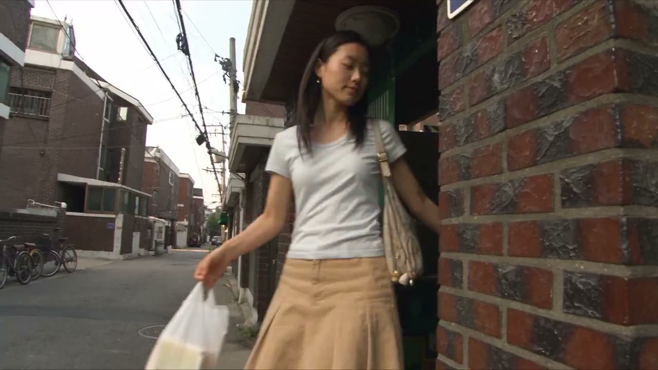 制作一段30秒的超写实2000年代初韩国DV数码摄像机家庭录像，内容是一位年轻的韩国女性在一个安静的下午探索首尔一处较老的住宅街区。整个过程中她的脸型、发型、…